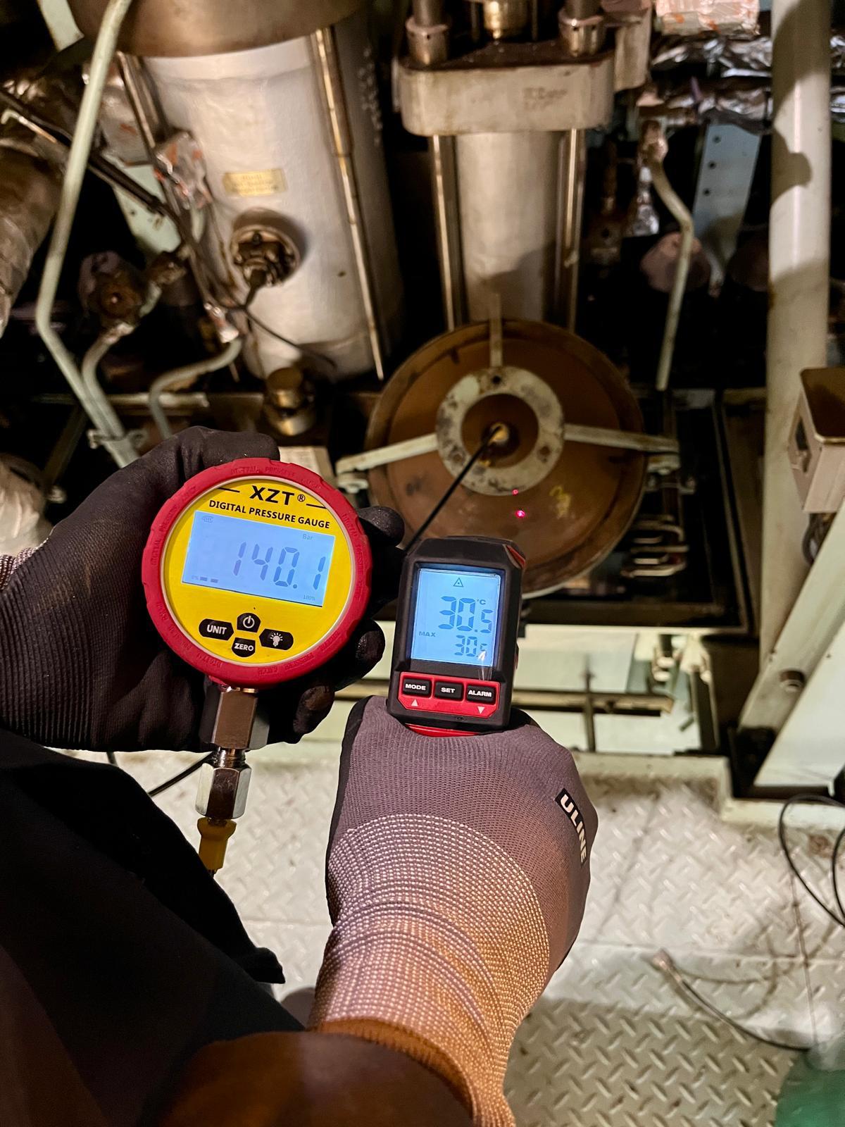 Engineer taking pressure and temperature readings with handheld gauges